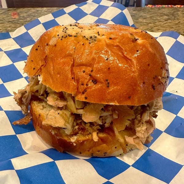 A Stuff'D Steaks & Hoagies cheesesteak sandwich with shredded meat and onions on a poppy seed bun.